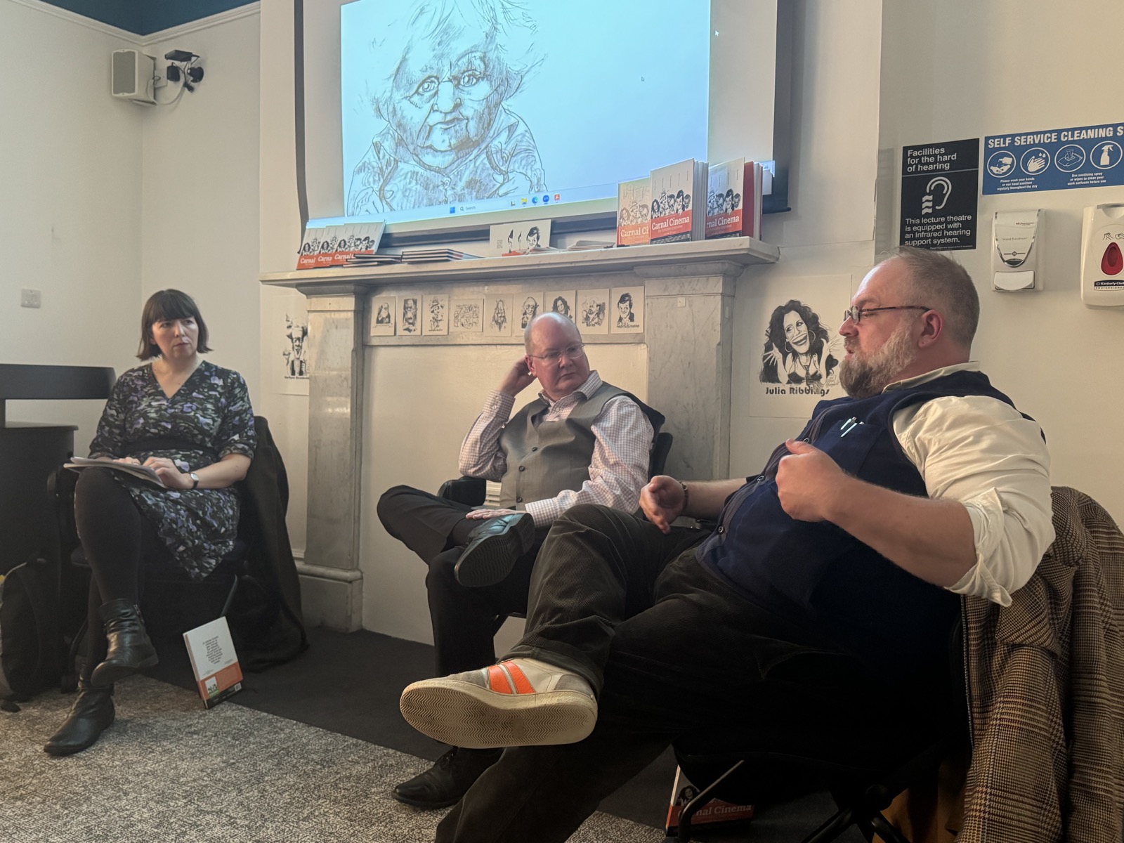 Kate Taylor, Andrew Lowes and Eric Dubois, a screen with Ken Russel stands behind