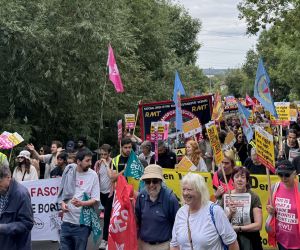 Hundreds of marchers walking through Epping Forest with banners.
